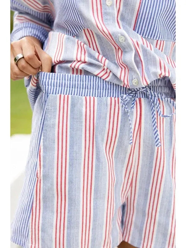 Woman wearing a blue and red striped shirt with a blurred outdoor background