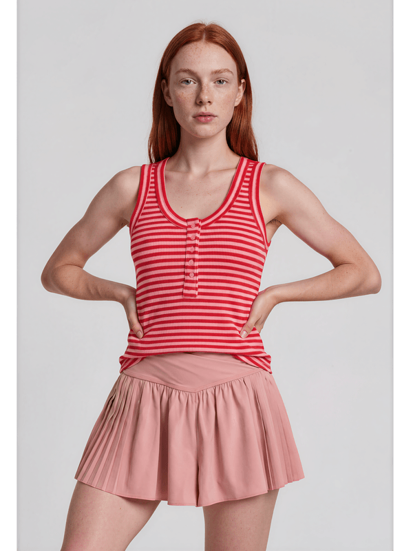 Woman wearing a red and white striped tank top and pink skirt on a light gray background