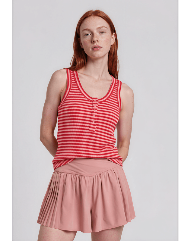 Woman wearing a red and white striped tank top and pink skirt on a light gray background