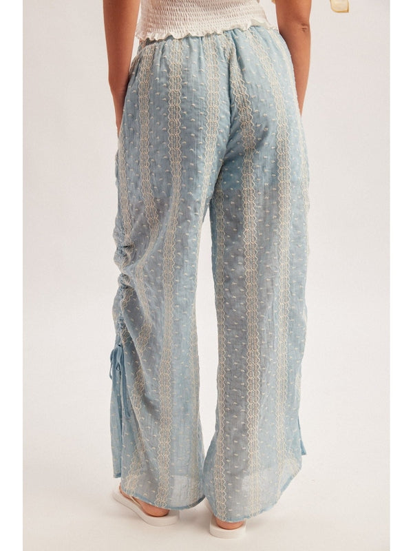 Woman wearing a white strapless top and light blue checkered pants on a plain background