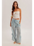 Woman wearing a white strapless top and light blue checkered pants on a plain background