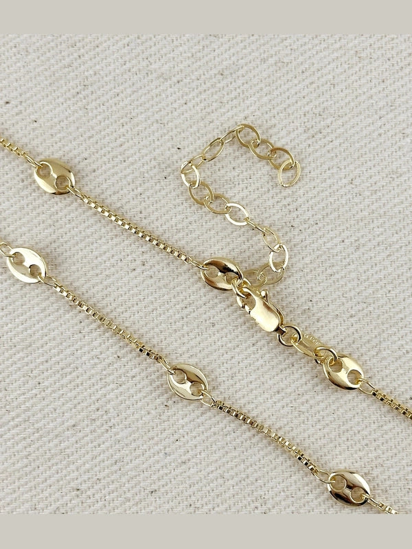 Gold chain necklace on a textured beige background