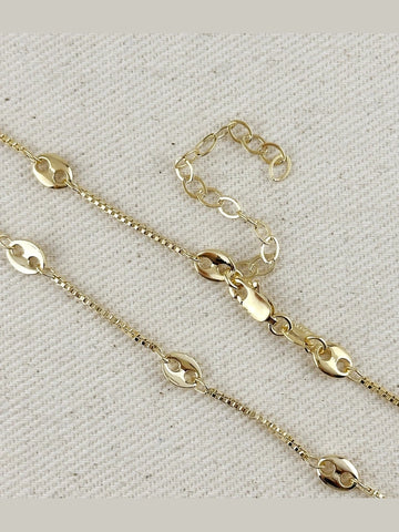 Gold chain necklace on a textured beige background