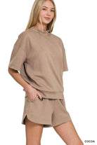 Woman wearing a beige outfit with shorts on a white background