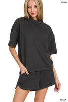 Woman wearing a black outfit with a matching top and shorts on a white background