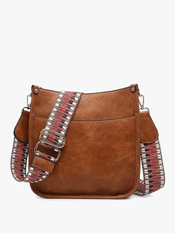 Brown leather handbag with decorative straps on a white background