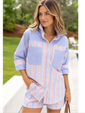 Woman wearing a blue and red striped shirt with a blurred outdoor background