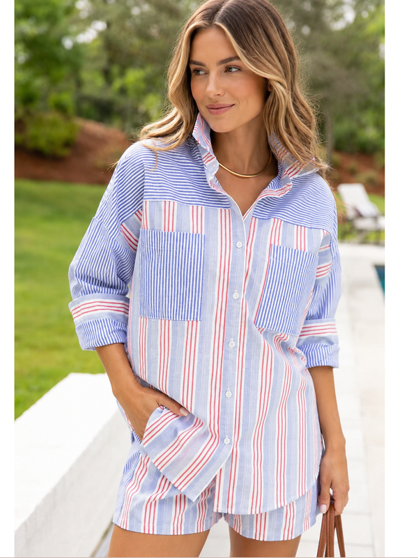 Woman wearing a blue and red striped shirt with a blurred outdoor background
