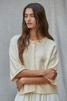 Woman wearing a cream-colored cardigan against a gray background