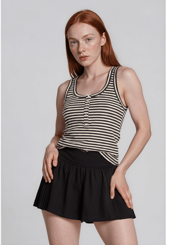 Woman wearing a black and white striped tank top and black skirt on a light gray background