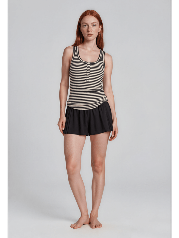 Woman wearing a black and white striped tank top and black skirt on a light gray background