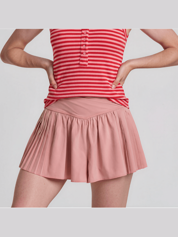 Person wearing a red and white striped shirt and pink pleated skirt on a light gray background