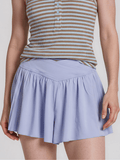 Person wearing a striped tank top and light purple skirt on a plain background
