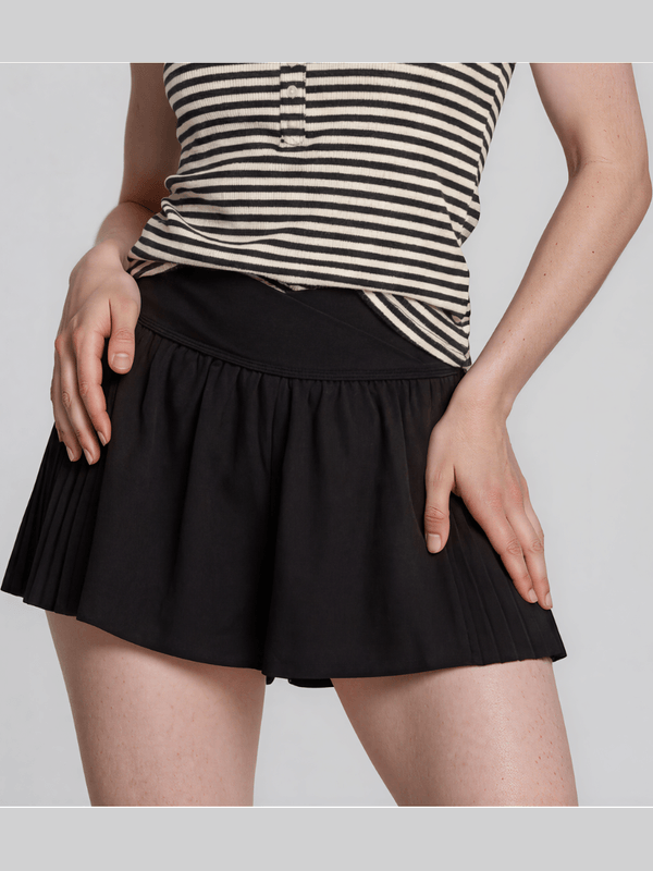 Person wearing a black skirt and striped top on a light gray background
