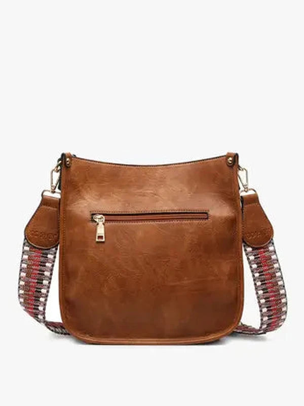 Brown leather handbag with decorative straps on a white background