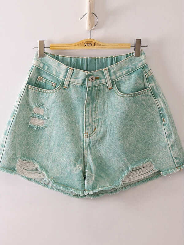 Denim shorts with distressed details on a hanger against a white background
