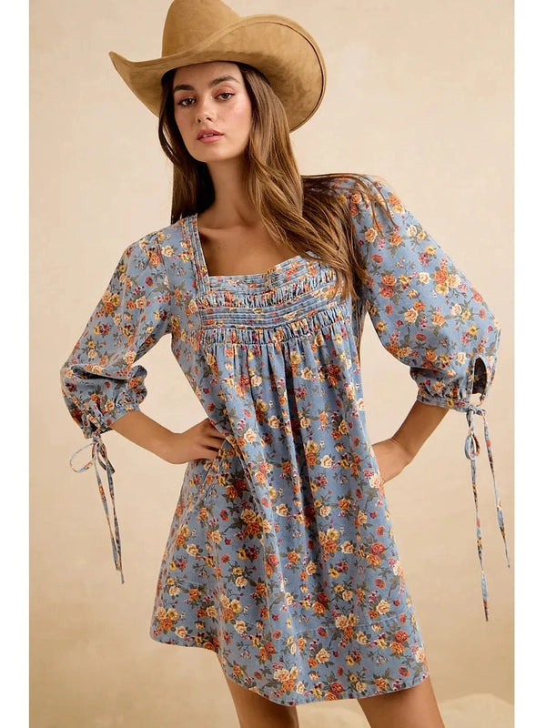 Woman wearing a floral dress and cowboy hat against a beige background