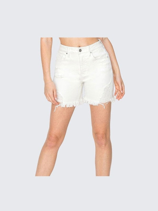Person wearing white denim shorts and cream ankle boots on a light gray background